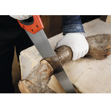 Osoba řeže dřevěné poleno ruční pilou na pracovním stole.