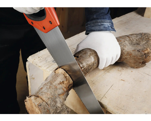 Osoba řeže dřevěné poleno ruční pilou na pracovním stole.