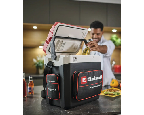 Akumulátorový chladicí box Einhell Power X-Change v kuchyni, muž vyndává láhev s pitím z otevřeného boxu s kapsami na příslušenství.