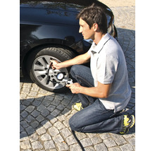 Muž kontroluje tlak v pneumatikách automobilu pomocí pneuhustiče s manometrem.