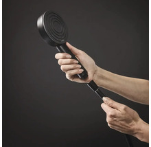 Ruka přišroubuje kulatou ruční sprchu Hansgrohe ke sprchové hadici.