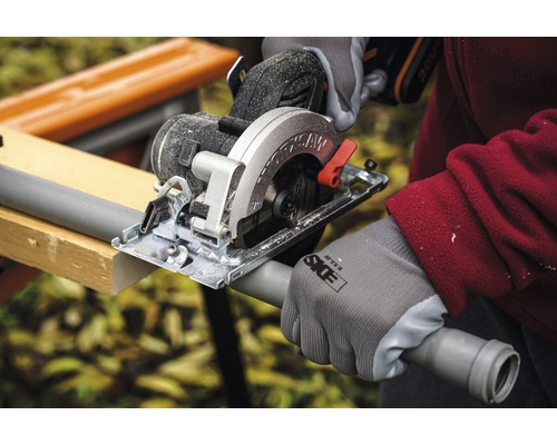 Ruční okružní pila řeže plastovou trubku na pracovním stole