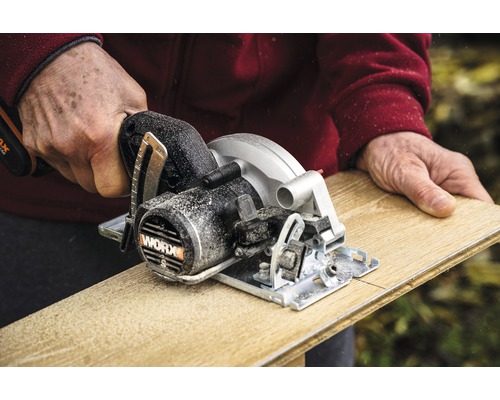 Osoba řeže dřevěnou desku ruční okružní pilou WORX.