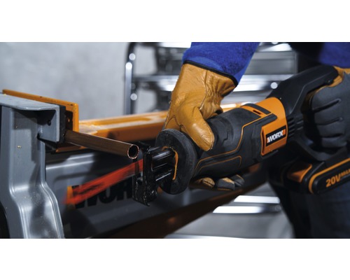 Osoba řeže měděnou trubku vratnou pilou značky Worx.