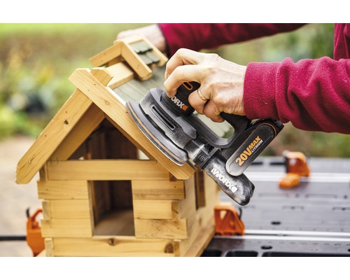 Osoba brousí ptačí budku excentrickou bruskou od společnosti Worx.