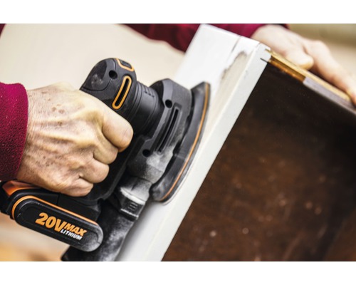 Osoba používá excentrickou brusku k broušení kusu dřeva.