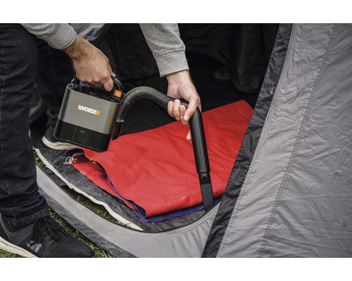 Osoba používá akumulátorový vysavač WORX ve stanu.