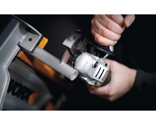 Osoba řeže trubku úhlovou bruskou v dílně. Logo Worx.