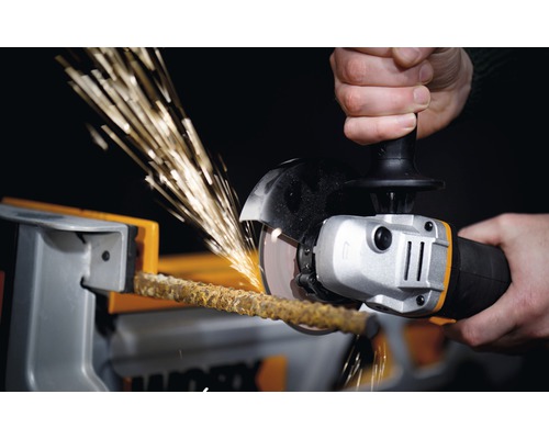 Osoba řeže tyč ve svěráku úhlovou bruskou, čímž vznikají jiskry.