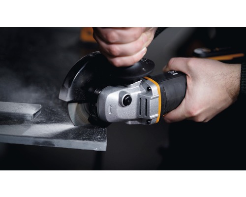 Ruka drží úhlovou brusku při broušení kusu kovu.