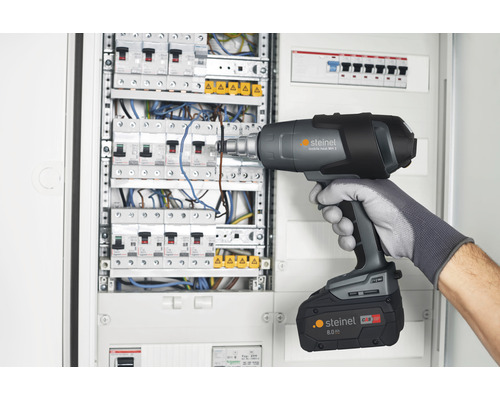 Muž používá horkovzdušnou pistoli Steinel na rozvodné skříni