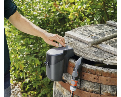 Automatické zavlažování zahrady se zavlažovacím čerpadlem namontovaným na dřevěném sudu.