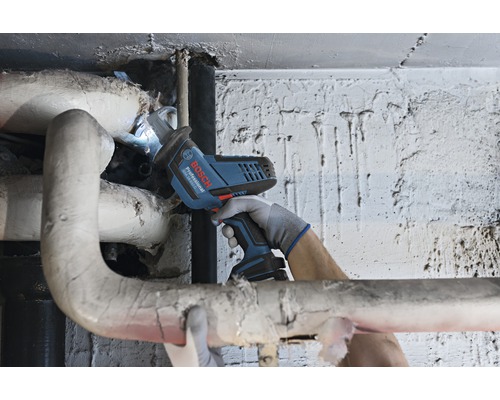 Akumulátorová pila v provozu na topné trubce, ovládaná osobou v rukavicích