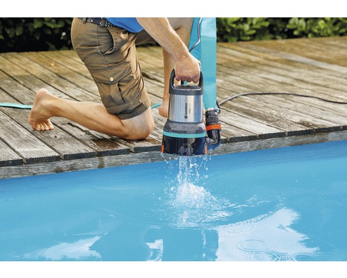 Muž vypouští vodu z bazénu pomocí kalového čerpadla Gardena.