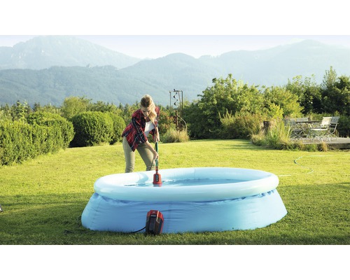 Žena používá bazénové čerpadlo k odstranění vody z nafukovacího bazénu na zahradě.