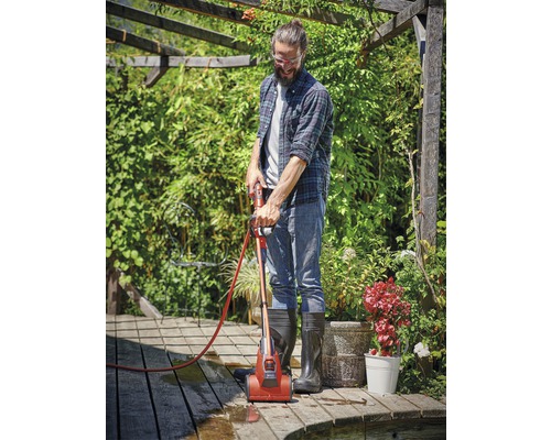 Muž čistí dřevěnou terasu čističem teras na zahradě