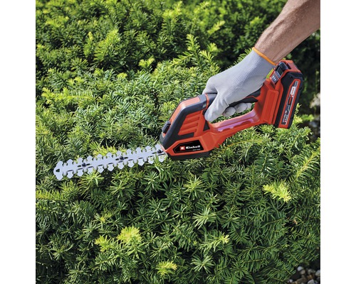 Osoba stříhá živý plot pomocí akumulátorových nůžek na živý plot Einhell.