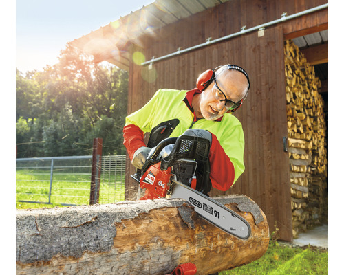 Muž řeže dřevo s motorovou pilou AL-KO venku.