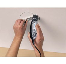 Osoba vyřezává otvor do stropu pomocí multifunkčního nástroje Dremel.