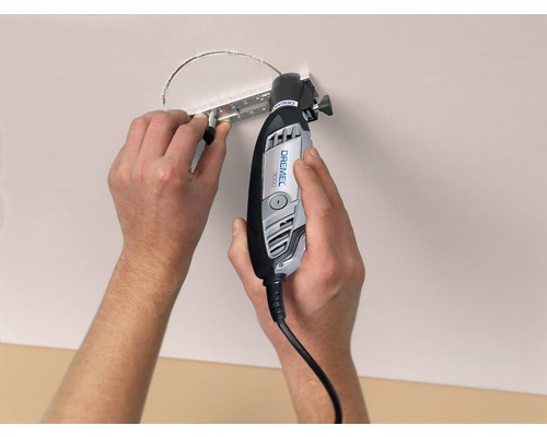 Osoba vyřezává otvor do stropu pomocí multifunkčního nástroje Dremel.
