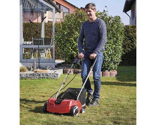 Muž používá provzdušňovač trávníku na zahradě.