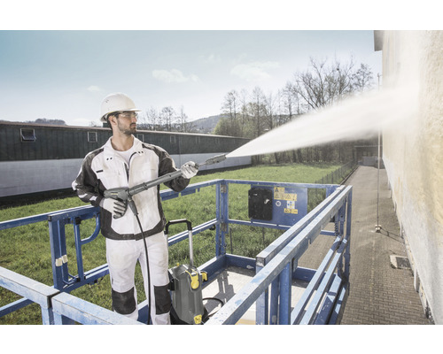 Muž čistí fasádu vysokotlakým čističem Kärcher na plošině.
