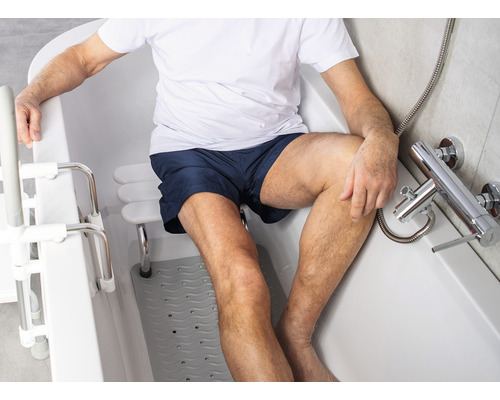 Muž sedí ve vaně se vstupní pomůckou a sedátkem do vany