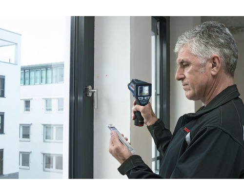 Muž používá termokameru k analýze okna.