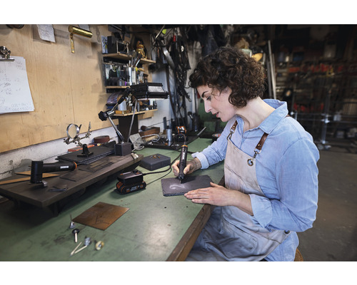 Žena gravíruje břidlicovou desku gravírovacím nástrojem na pracovní stůl