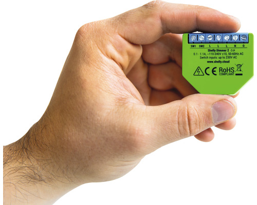 Ruka drží stmívač Shelly Dimmer 2 pro domácí automatizaci