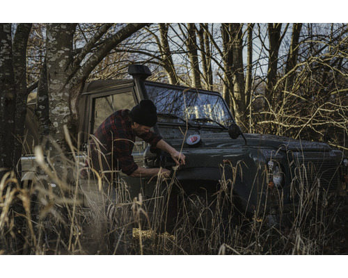 Muž opravuje terénní vozidlo v přírodě