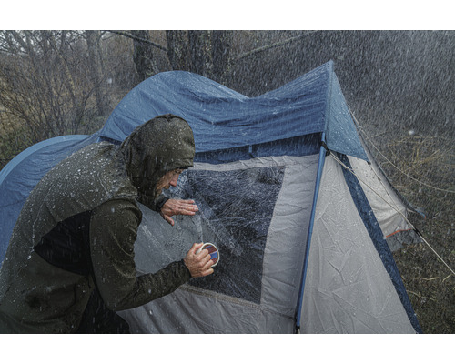 Osoba čistí okno stanu za deštivého počasí.