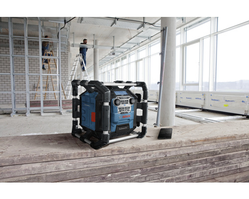 Staveništní rádio Bosch na staveništi se stavebními dělníky a stavebními materiály