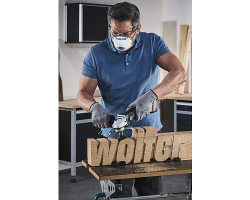 Muž formuje nápis dřevo pomocí dřevoobráběcího kotouče.