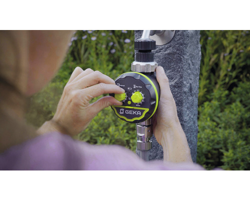 Osoba nastavuje ovladač zavlažování GEKA, který je připevněn k vodovodnímu kohoutku.