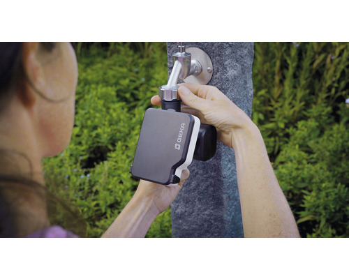 Osoba upevňuje zavlažovací ovladač Geka na zahradní kohoutek.