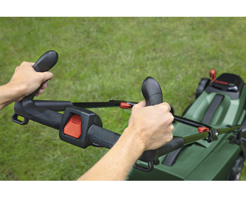 Osoba obsluhuje sekačku na trávu na trávníku.