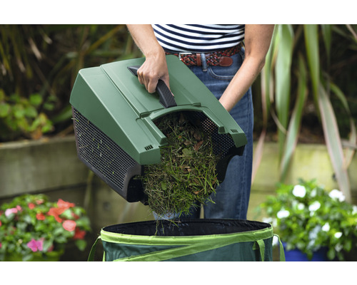 Osoba vyprazdňuje trávu a listí pomocí sběrače listí do zahradního pytle.