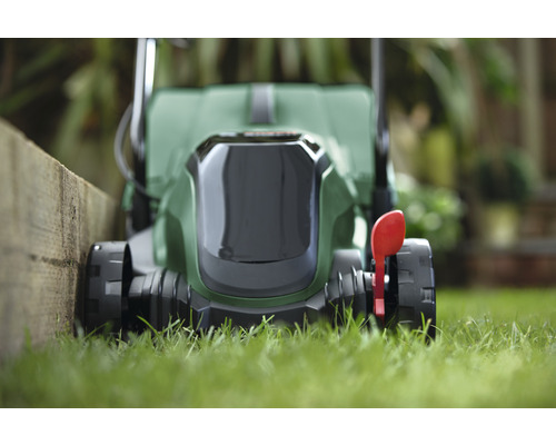 Sekačka na trávu na trávníku poblíž zahrady