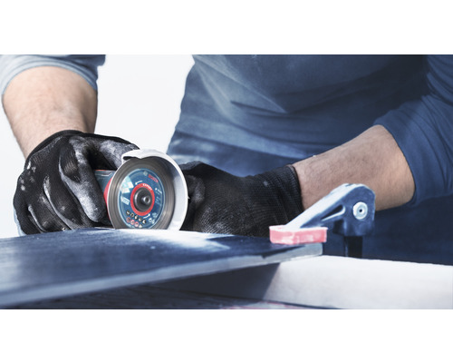 Řemeslník řeže dlaždice pomocí rozbrušovací pily