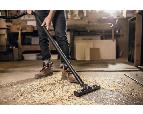 Osoba vysává dřevěné hobliny vysavačem.