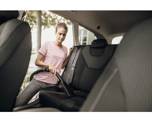 Žena vysává autosedačky vysavačem.