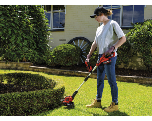 Žena používá akumulátorový vyžínač na zahradě.