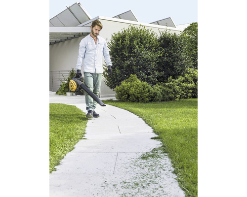 Muž čistí chodník pomocí foukače listí