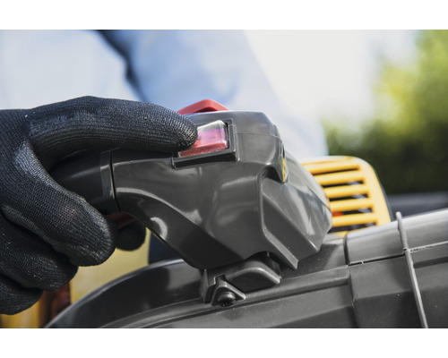 Ruka s ochrannou rukavicí ovládá spínač foukače listí