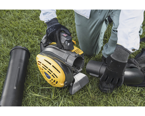 Osoba montuje žlutošedý vysavač listí na trávníku.