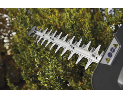 Řezací zařízení nůžek na živý plot v provozu před živým plotem.