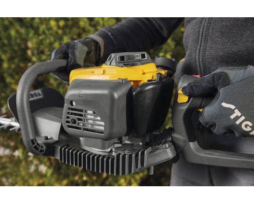 Osoba drží žluté a šedé nůžky na živý plot