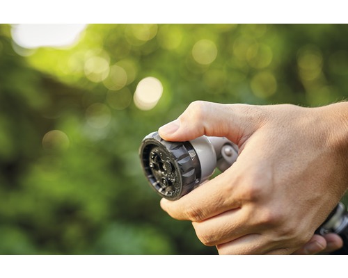 Ruka drží stříkací hlavici zahradní hadice