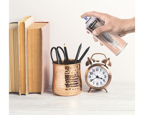 Scéna s knihami, držák na pera s pery, budík a plechovka metalického spreje